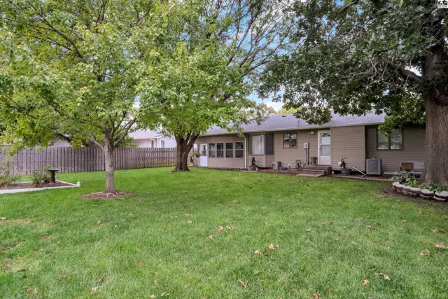 Spacious backyard with mature trees and a wooden fence surrounds this home.