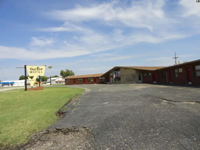 This motel features a single-story brick building with a pitched roof and a large sign.