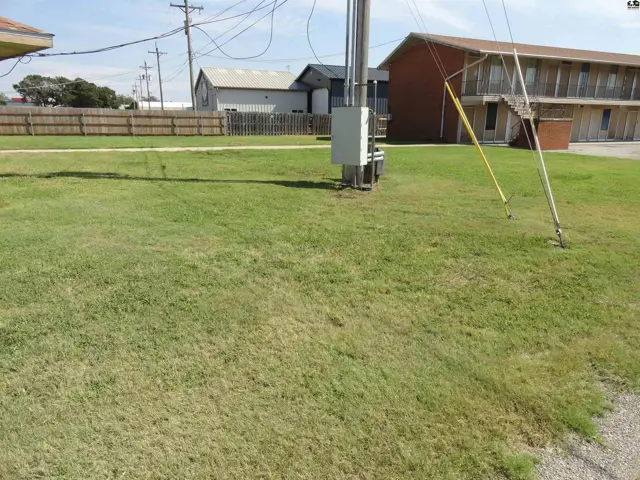 A brick building with exterior stairs sits adjacent to a grassy lawn.