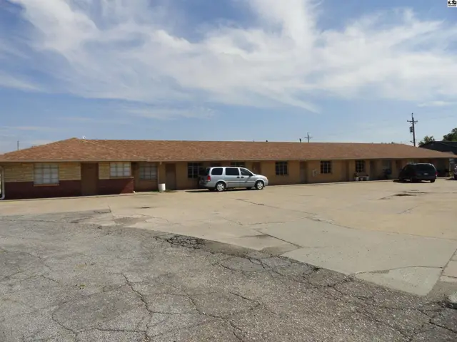 Single-story brick building with a long, low-pitched roof and a paved parking lot.