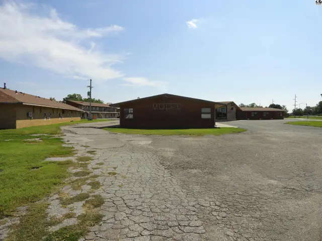 Brick building with asphalt parking lot and surrounding grass areas.