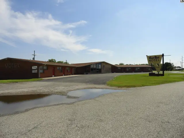 Single-story brick building with a paved lot and grassy areas.