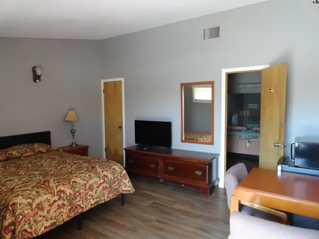 This room features a bed, dresser with television, and a small desk.