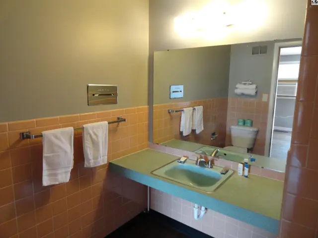 This bathroom features a mint green sink, coral tile, and a large mirror.