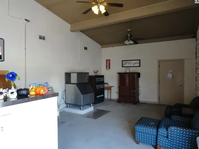 Spacious room with vaulted ceiling, ceiling fans, and concrete floor.