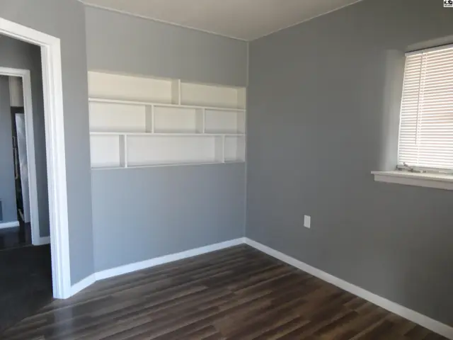 This room features grey walls, built-in shelving, and wood-look flooring.