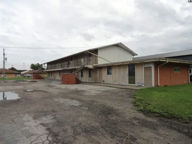 Two-story building with exterior stairs, brick accents, and a paved lot.