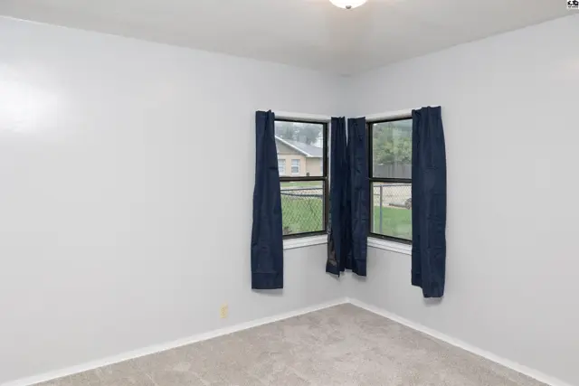 Corner room with light grey walls, grey carpet, and dark blue curtains.