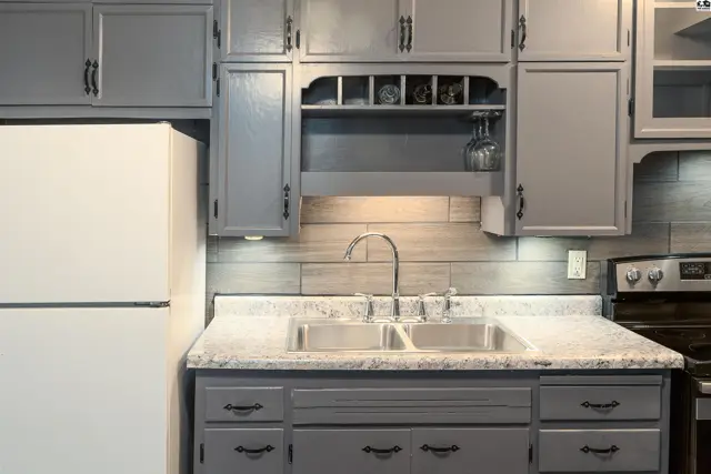 Kitchen features gray cabinetry, granite countertops, and a stainless steel sink.