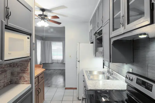 This kitchen features grey cabinetry, a double sink, and a stainless steel range.