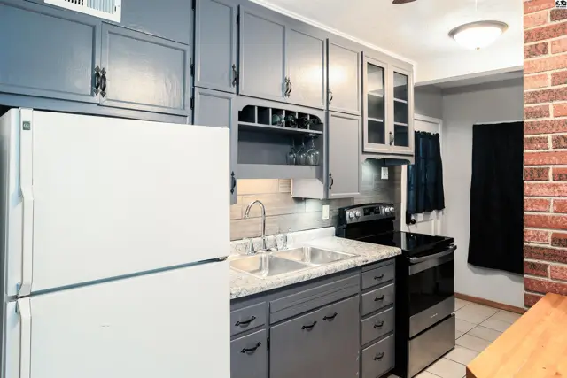 Gray cabinets, granite countertops, and stainless steel appliances fill this kitchen.