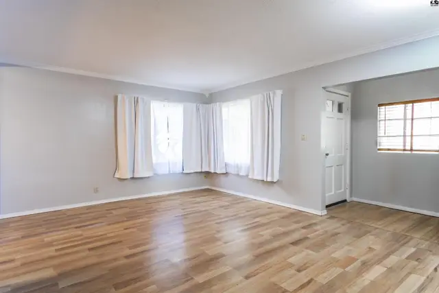 Spacious living area with light wood floors and large windows.