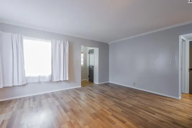 Spacious living area with hardwood floors and large windows.