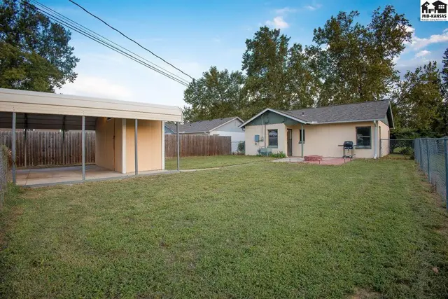 A fenced yard surrounds this home with a detached carport and a small patio.