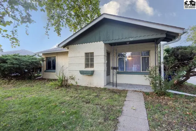 This stucco home features a covered porch and mature landscaping.