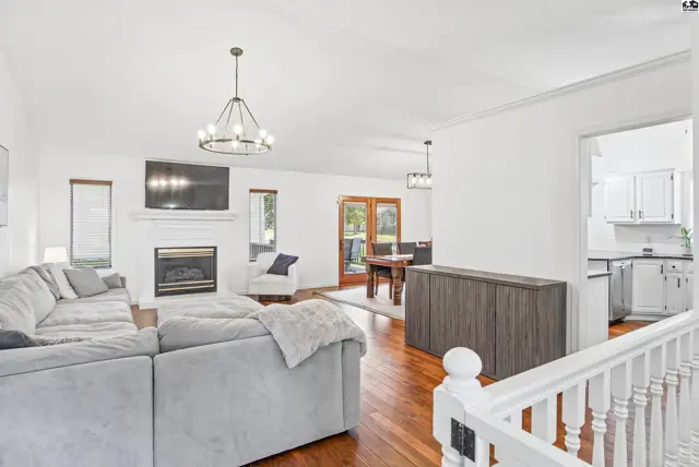 Spacious living area with fireplace, hardwood floors, and access to dining and kitchen.