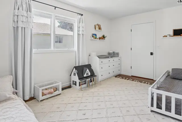 This room features white walls, a large window, and a white dresser.