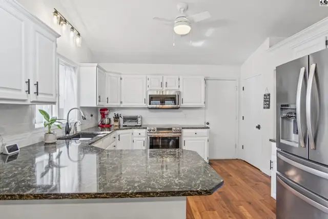 White cabinets, granite countertops, stainless steel appliances, and hardwood floors define this spacious kitchen.