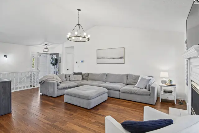 Spacious living room with vaulted ceiling, fireplace, and hardwood floors.