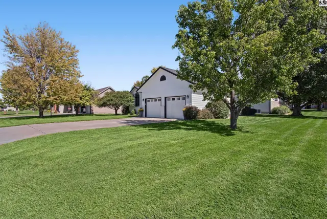 White detached garage with two doors sits on a manicured lawn.