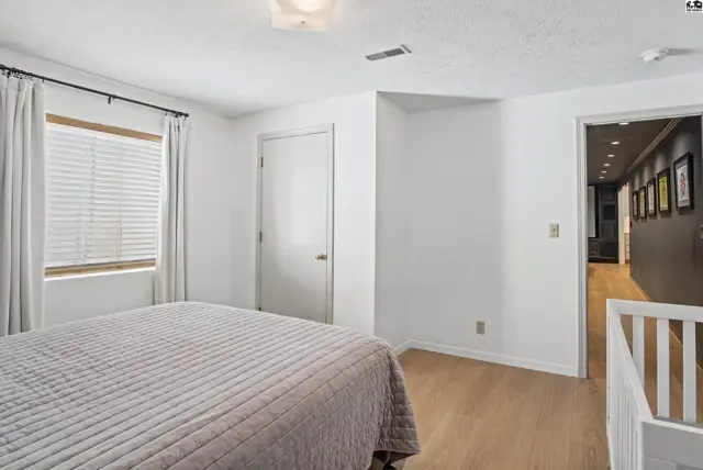 This bedroom features a large window, a closet, and light wood flooring.