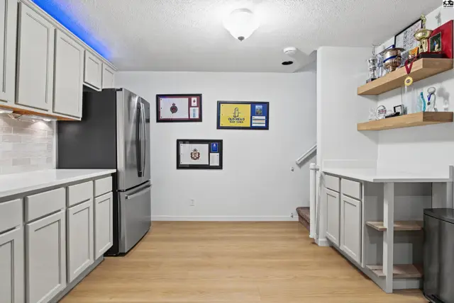 Modern kitchen features light wood floors, white countertops, and grey cabinetry.