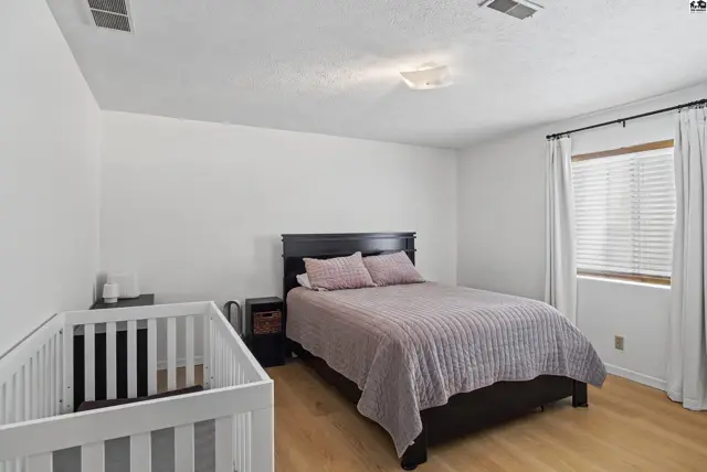 Spacious bedroom with a king-sized bed, nightstand, and a white crib.