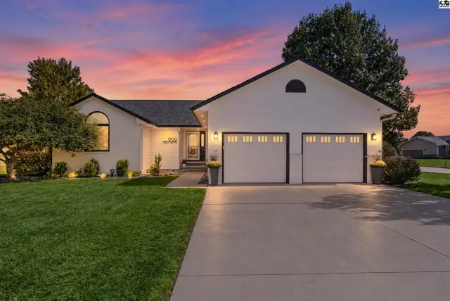 Modern white stucco home with a black roof, two-car garage, and manicured lawn.