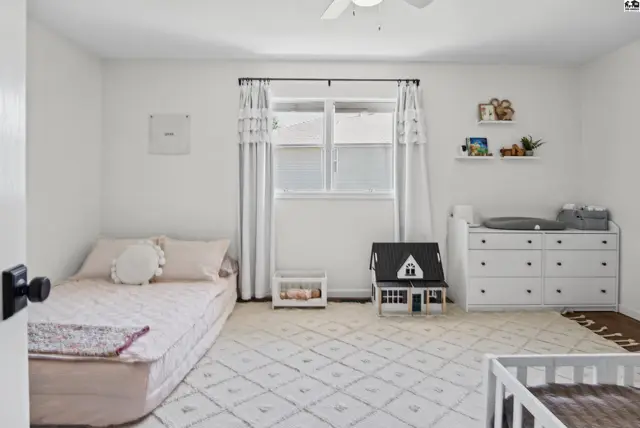 This room features a bed, dresser, rug, and a ceiling fan.