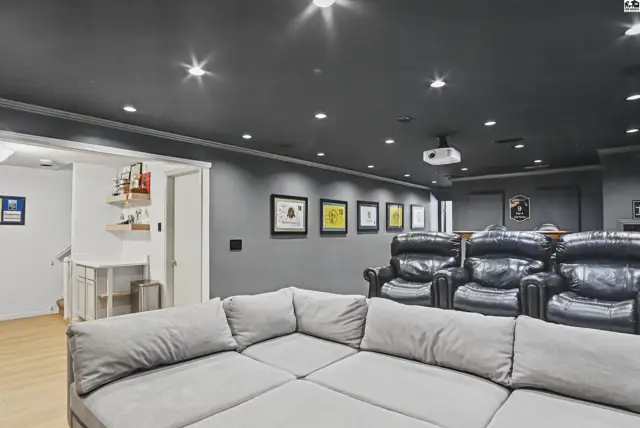 This room features a large sectional sofa, plush recliners, and a projector screen.