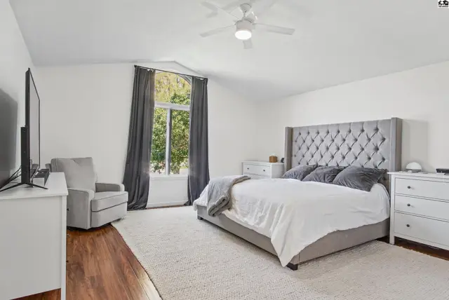 Spacious bedroom with a king-sized bed, plush rug, and large window.