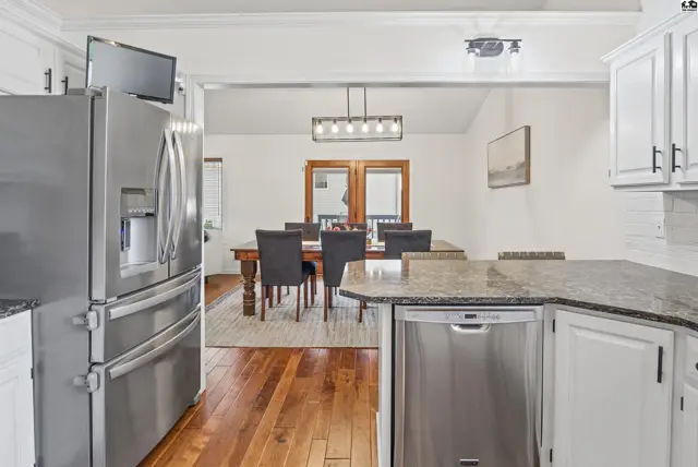 Stainless steel appliances complement the granite countertops and white cabinetry in this kitchen.