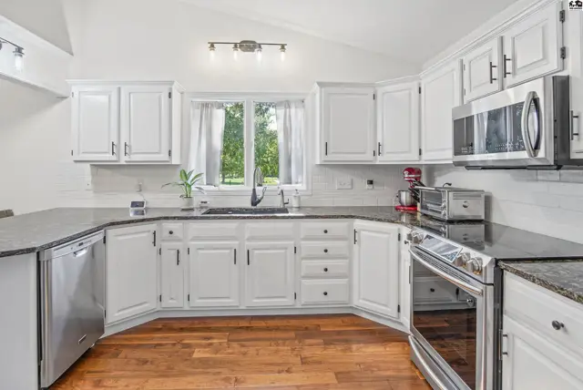 White cabinets, granite countertops, stainless steel appliances, and hardwood floors define this spacious kitchen.
