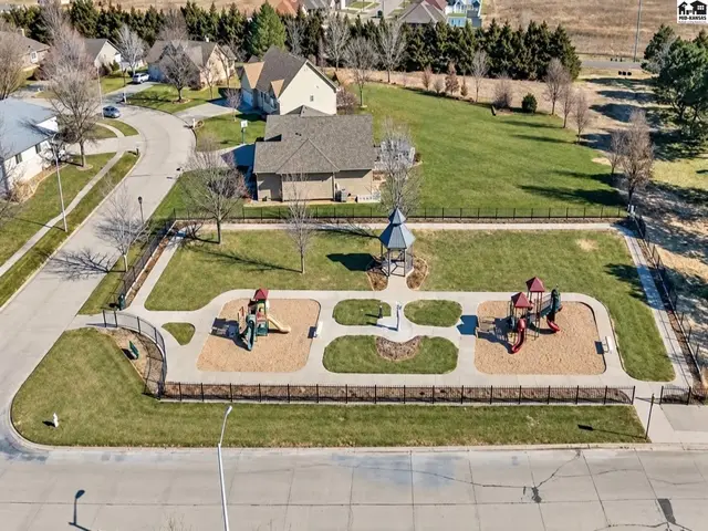 Fenced park area features two playground structures and a covered gazebo.