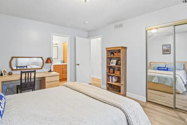 This bedroom features a desk, mirrored closet doors, and a doorway to an ensuite bathroom.