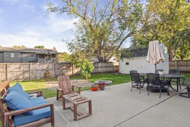 Spacious backyard features a concrete patio, fire pit, and a storage shed.