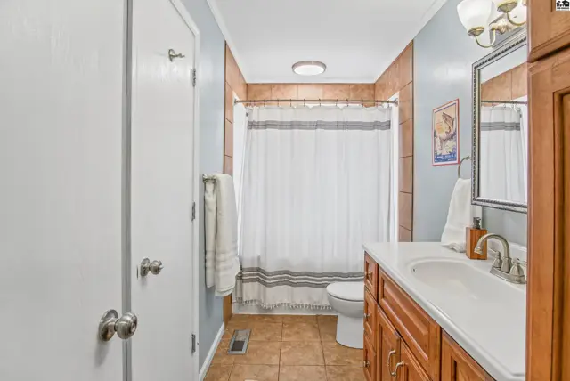 This bathroom features a vanity, toilet, and tiled shower with a curtain.