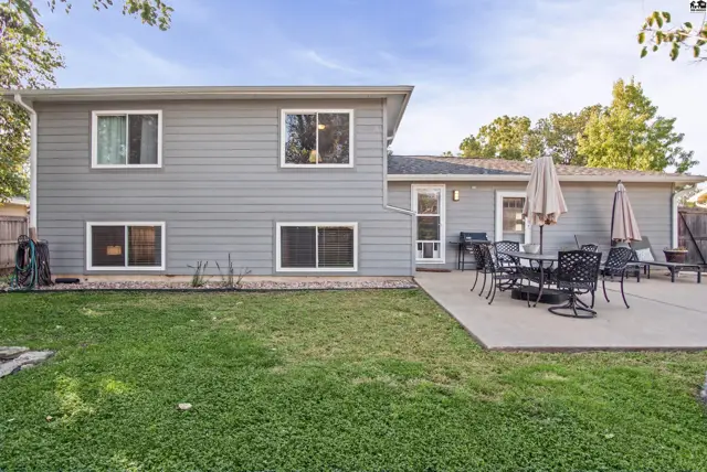 Gray-sided house with a concrete patio and green lawn.