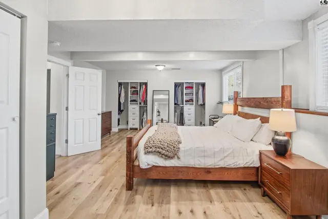 Spacious bedroom with hardwood floors, built-in closets, and a wooden bed frame.