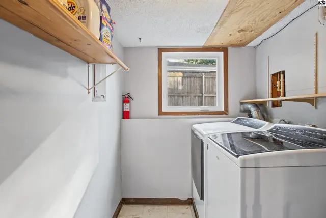 This laundry room features white walls, a wooden window frame, and two appliances.