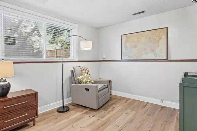 This room features light wood flooring, a large window, and a map on the wall.