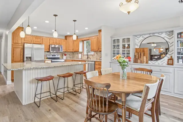 Spacious kitchen features granite countertops, wood cabinetry, and a large island with seating.