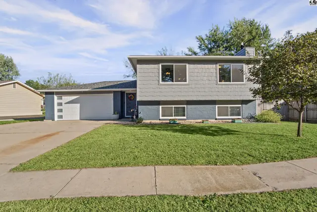 This two-story home features a gray exterior, attached garage, and a manicured lawn.