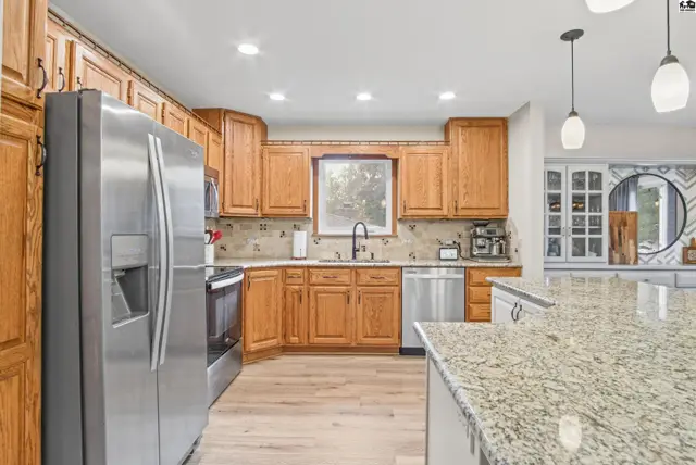 Spacious kitchen features granite countertops, stainless steel appliances, and ample oak cabinetry.