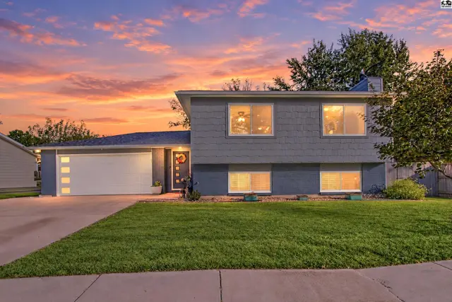 This two-story home features a gray exterior, attached garage, and manicured lawn.