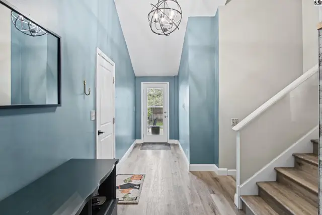 Hallway with light wood floors, blue walls, and a modern light fixture.