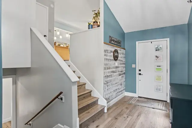 This entryway features a white door, light wood flooring, and a textured accent wall.