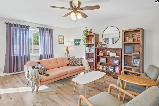 Living room features a pink sofa, wood bookshelves, and a ceiling fan.