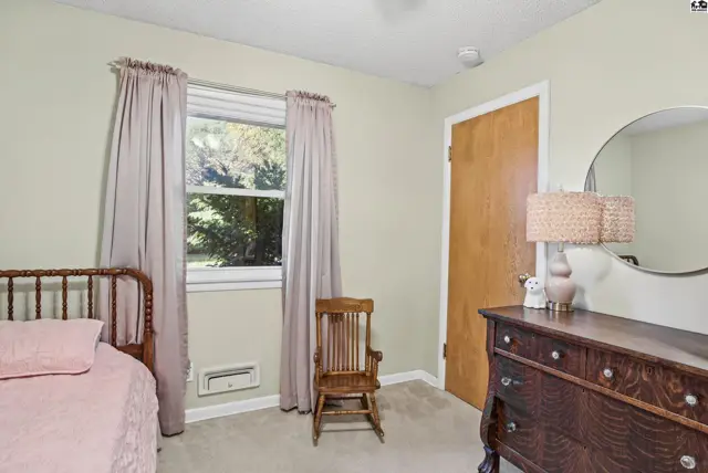 This bedroom features a wooden bed frame, a rocking chair, and a dresser with a mirror.
