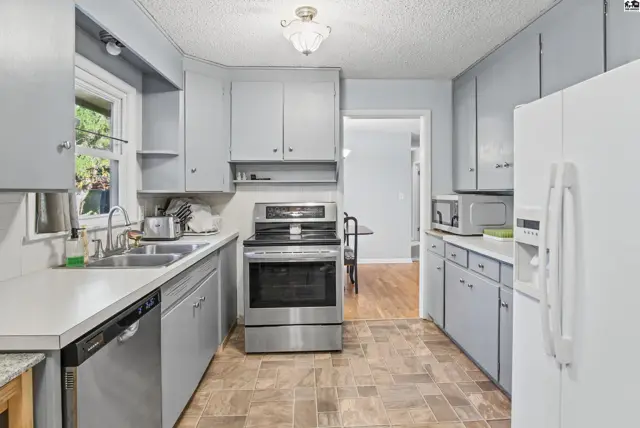 This kitchen features light gray cabinets, a stainless steel range, and a white refrigerator.